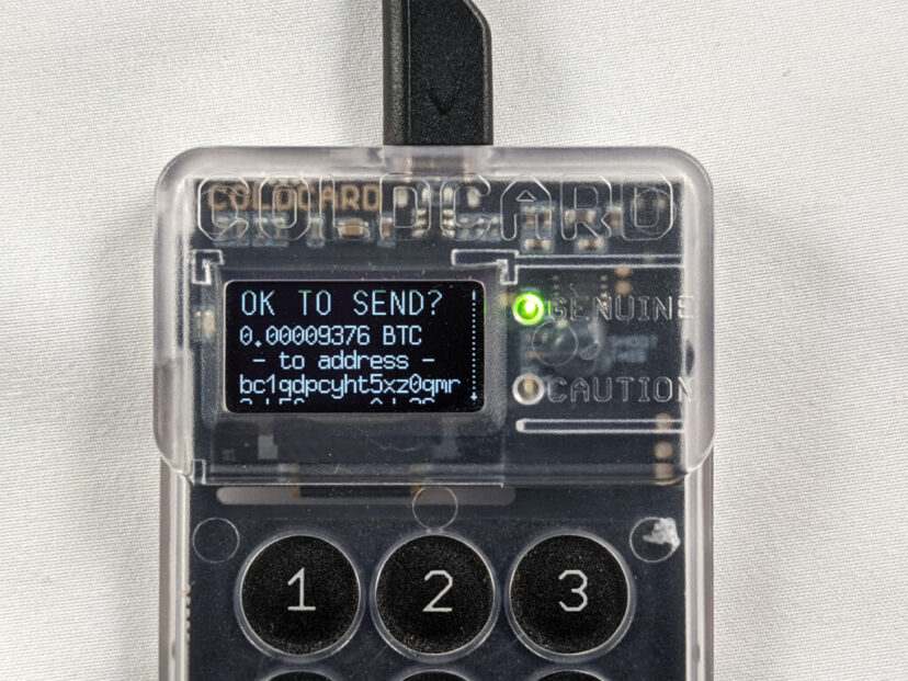 Hardware wallet device on dark background with warning sign and bitcoin symbol, security breach concept