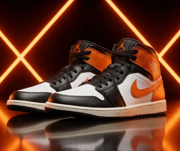 Кроссовки Air Jordan в чёрно-оранжево-белой расцветке на чёрном фоне с оранжевой неоновой