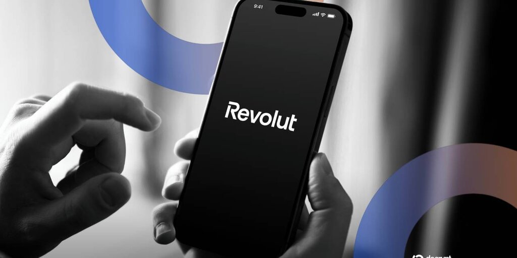 Человек держит смартфон с логотипом Revolut на экране