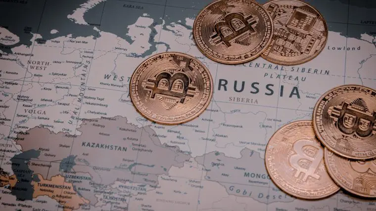 Золотистые монеты с символом биткоина лежат на карте России